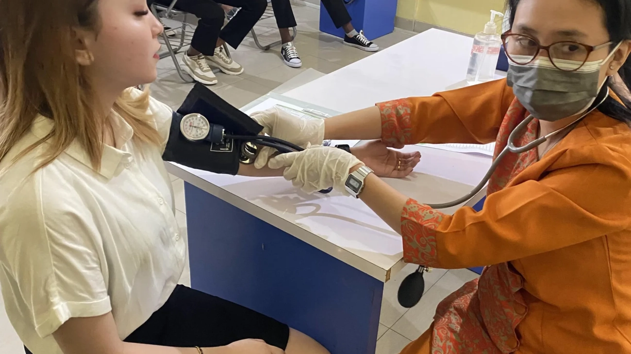 sekolah penerbangan makassar. Tenaga kesehatan mengukur tekanan darah wanita di ruang pelatihan.