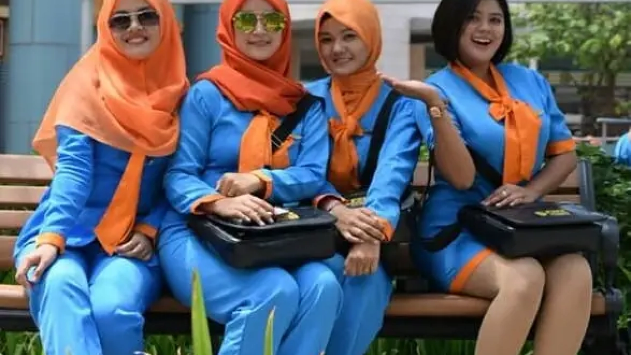 Diklat Staff Bandara. Empat wanita berseragam biru oranye tersenyum ceria.