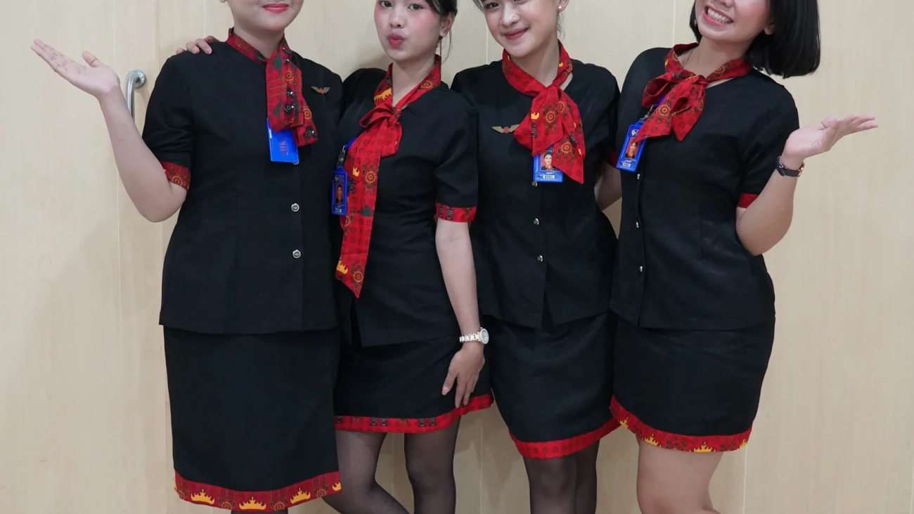 Seragam Pramugari Prestisius. Empat pramugari tersenyum dalam seragam hitam merah.